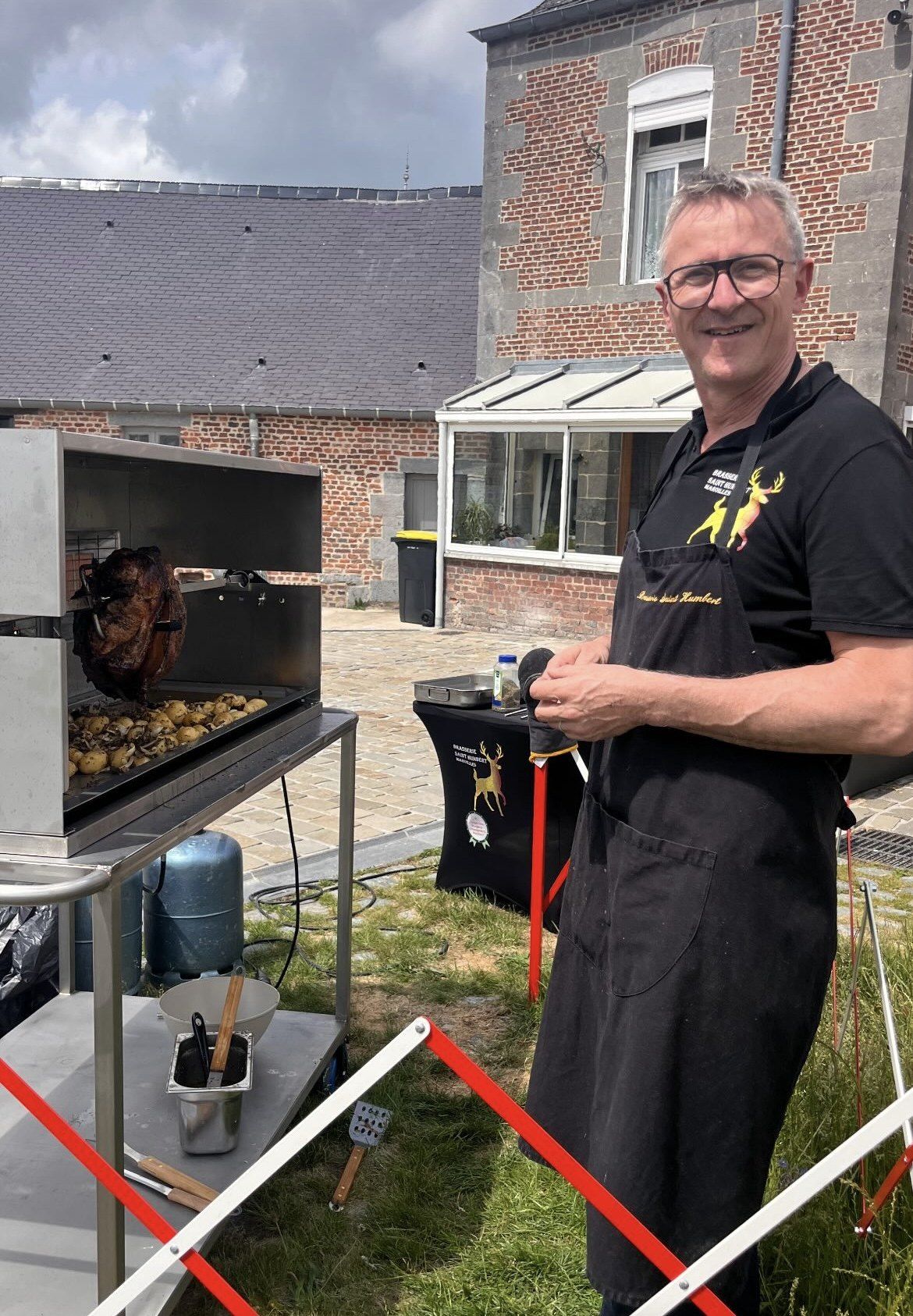 Le brasseur devant la rôtissoire du jambon à la broche, en terrasse